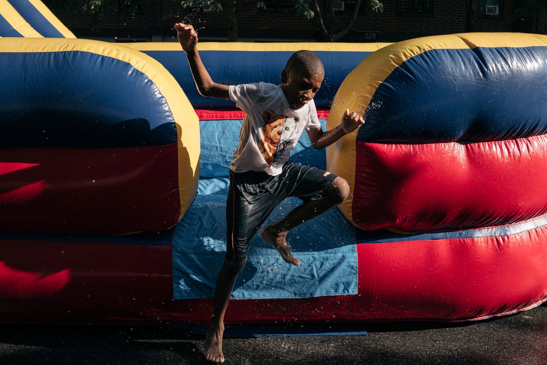 Kids play in an inflatable water slide on Greene Avenue in Bed Stuy during a block party.
